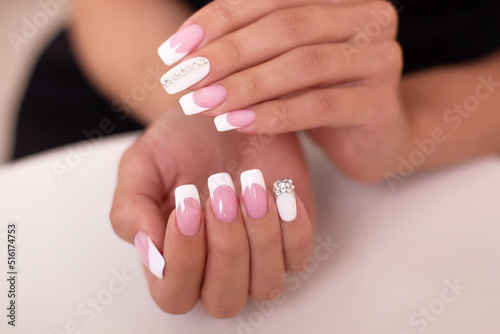  Close up view of beautiful female hands with luxury french manicure nails on white background 