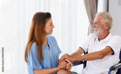 female doctor helping care holding hands to encourage talk Caucasian older man, older adult, patient in a wheelchair