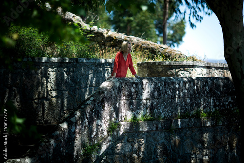 A woman on a stone staircase in a medieval park.