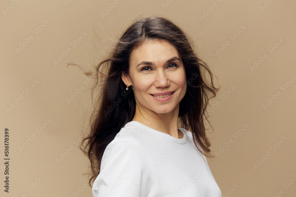 portrait of a sweet, beautiful, charming, pleasant woman with black hair, blowing in the wind, in a white T-shirt. Studio photo on a plain background portrait of a sweet, beautiful, charming, pleasant woman with black hair, blowing in the wind, in a white T-shirt. Studio photo on a plain background