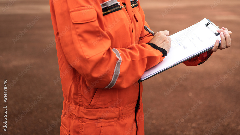 Action of safety officer is writing and check on checklist document during safety audit and inspection at drilling site operation. Industrial expertise occupation working scene. Action of safety officer is writing and check on checklist document during safety audit and inspection at drilling site operation. Industrial expertise occupation working scene.