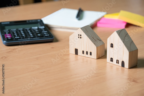 Wooden house model with calculator and paper note on wood table. Saving plan and interest rate to buy property, house. Personal financial concept for own a house. with copy space for text