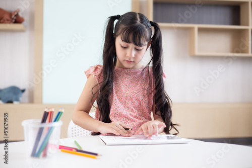 Little girl drawing on the table in the house