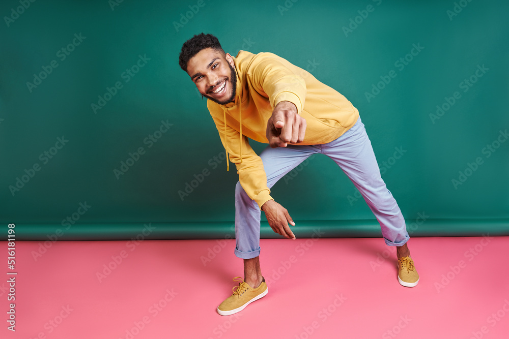 Happy African man looking at camera while standing against colorful background