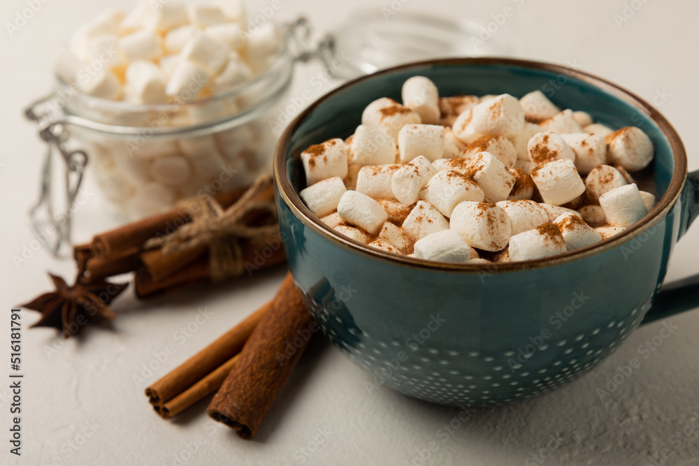 Cup of tasty cocoa drink and marshmallows in blue cup.Spices and marshmallows for winter drinks on white texture table.Winter hot drink.Hot chocolate with marshmallow and spices.Copy space.