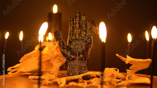 Fortune teller hand or palmistry on the witch table with animal bones and insects. Black palm and candles with cicadas bugs. Magic alchemy spirituality symbol. Palm reading in mystic, occult room.