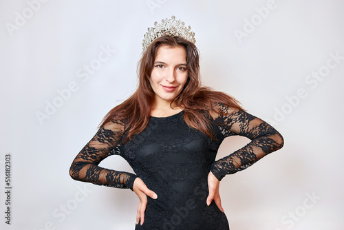 A beautiful girl in a black dress with a crown on her head. Beauty contest concept.