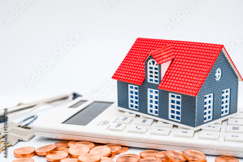 House model, calculator, coins and keys on white background - house buying concept image