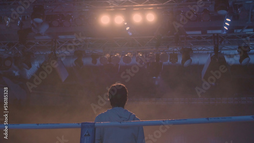 Back view of working gaffer or lighting technician and spotlights background. Lighting technician, placing the light during a film. Lighting technicians operating strobes during a concert