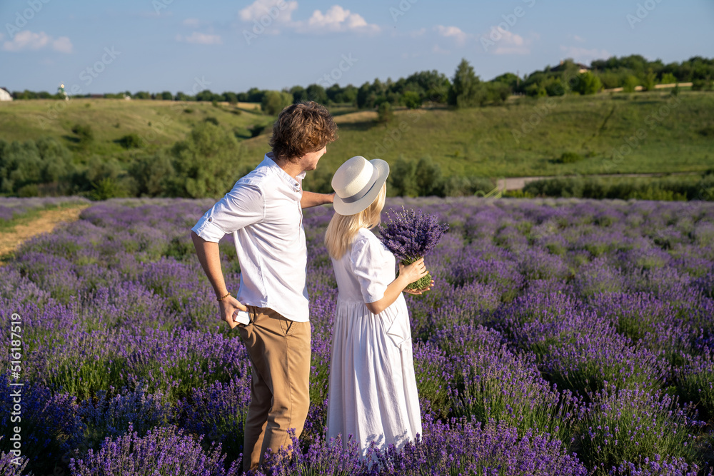 Fototapeta premium couple in white outfit in lavender field, photo session. man is proposing to woman with ring. engagement day. romance and true love in relationship