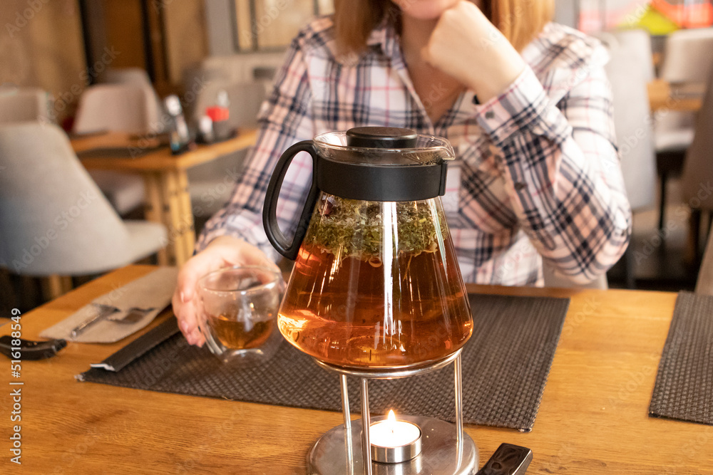 a girl drinks tea in cafe. teapot with tea on the table