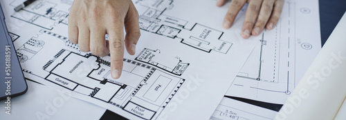 Architectural building design and construction plans with blueprints, Young man was designing a building or architecture with a ruler, pen, pencil, tape measure, architect hat and other equipment.