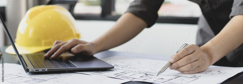 Young man with a laptop plotting a system of building structures in ...
