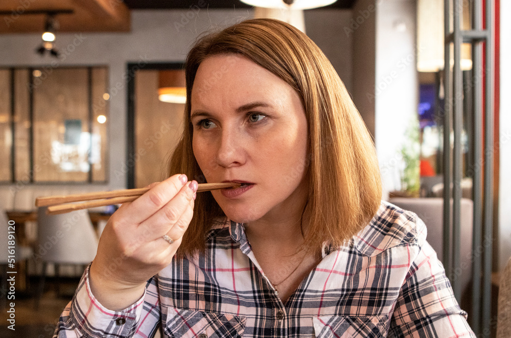 a girl eats japanese food with chopsticks in a restaurant. a girl eats japanese food with chopsticks in a restaurant.