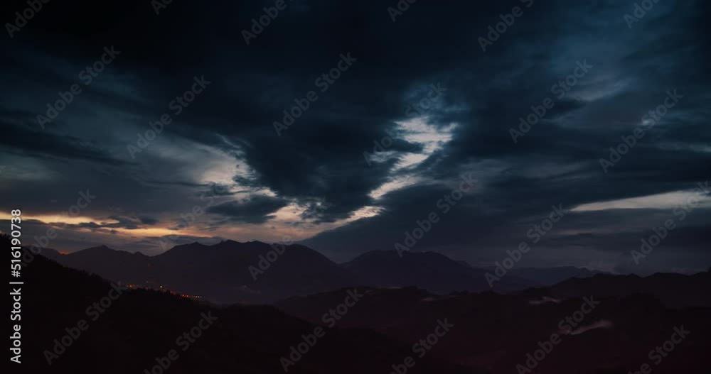 Late evening timelapse of cloudy sky in mountains landscape at sunset. Hyperlapse footage of clouds moving on the sky after stormy rain with city light on background