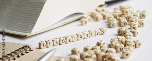 Word linguistics on a white background next to an open book, notepad, fountain pen and many letters. Concept of the study of the humanities and modern linguistic studies. Selective focus.