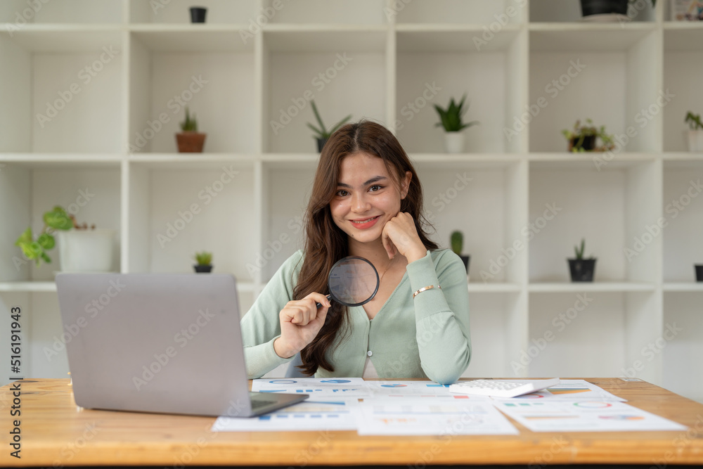Business analyst using magnifying to review financial graphs, charts. Concept of Analyze return on investment and business analytics growth. Business analyst using magnifying to review financial graphs, charts. Concept of Analyze return on investment and business analytics growth.