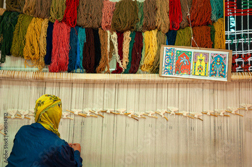 Villager worker woman with scarf weaving traditional Turkish carpet with colorful wools. Woman working at the manufacture of carpets. Cappadocia, Turkey.