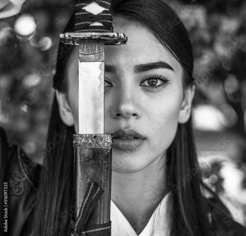 Close-up portrait of an elegant girl lady in form of samurai with steel sword katana female prowess and courage in penetrating look, black and white photo © okostia