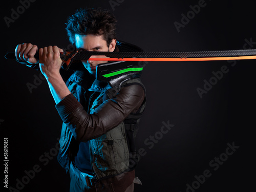 A guy in a cyberpunk image, holding a tuned sword in his hands. Cyborg samurai. A young man in neon lighting on a black background