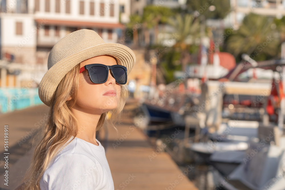A beautiful young girl stands in the marina and looks up.