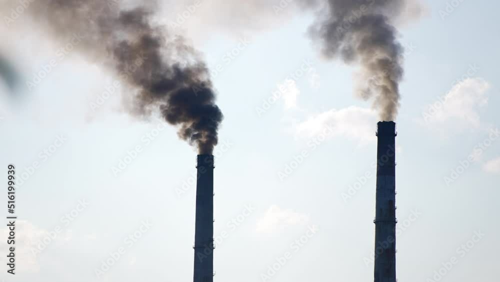 Dark silhouettes of factory pipes producing dark smoke into the sky. Air pollution from industry. Light blue sky backdrop. Dark silhouettes of factory pipes producing dark smoke into the sky. Air pollution from industry. Light blue sky backdrop.