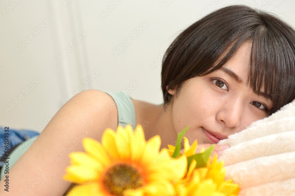 ヒマワリと室内でくつろぐキャミソール姿の若い女性のポートレート ヒマワリと室内でくつろぐキャミソール姿の若い女性のポートレート