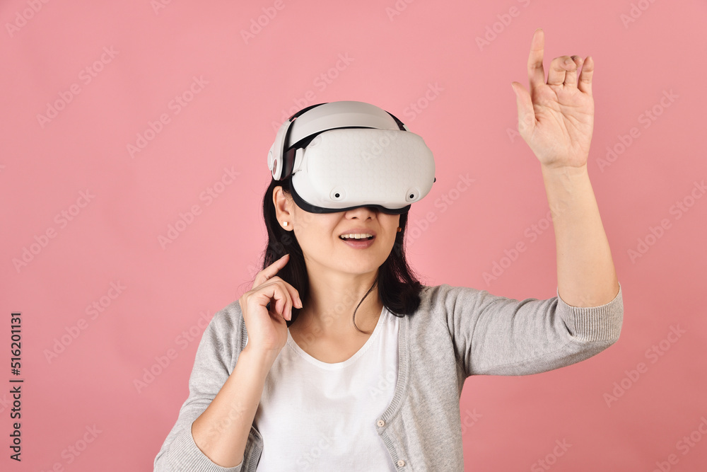 Asian woman using vr glasses, Hand grabbing something from virtual reality headset, Young woman having fun with new experience by vr technology, Studio shot. Asian woman using vr glasses, Hand grabbing something from virtual reality headset, Young woman having fun with new experience by vr technology, Studio shot.