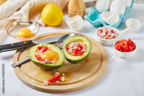 Avocado with egg, ham, tomatoes and cheese. Keto lunch recipe. Before baking