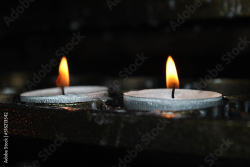 Zdjęcie przedstawiające dwa palące się znicze na ciemnym tle