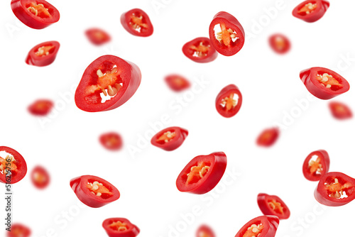 Falling sliced red hot chilli peppers isolated on white background, selective focus