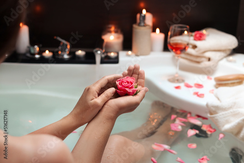 Woman holding rose flower while taking bath  closeup. Romantic atmosphere
