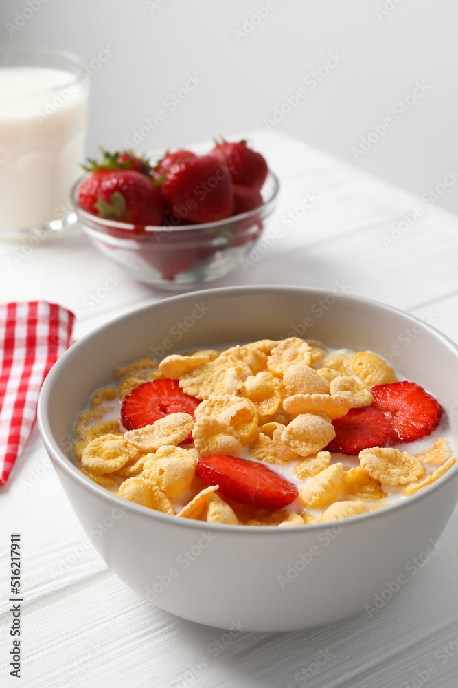 Corn flakes with strawberries in bowl served on white wooden table Corn flakes with strawberries in bowl served on white wooden table