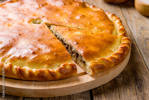 Ossetian pie with meat on wooden table macro close up photo