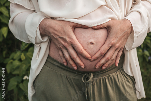 pregnant woman holding her hands on her stomach, close-up
