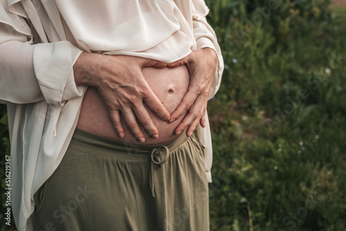 pregnant woman holding her hands on her stomach, close-up