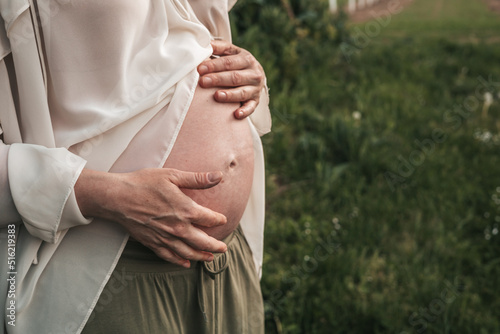 pregnant woman holding her hands on her stomach, close-up