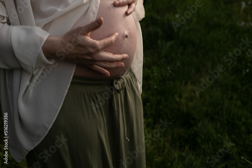 pregnant woman holding her hands on her stomach, close-up