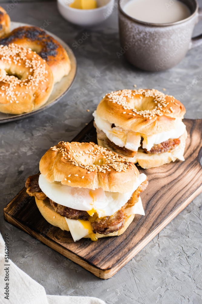 Bagels sandwiches with cheese, fried meat and poached egg. Homemade fast food. Vertical view Bagels sandwiches with cheese, fried meat and poached egg. Homemade fast food. Vertical view