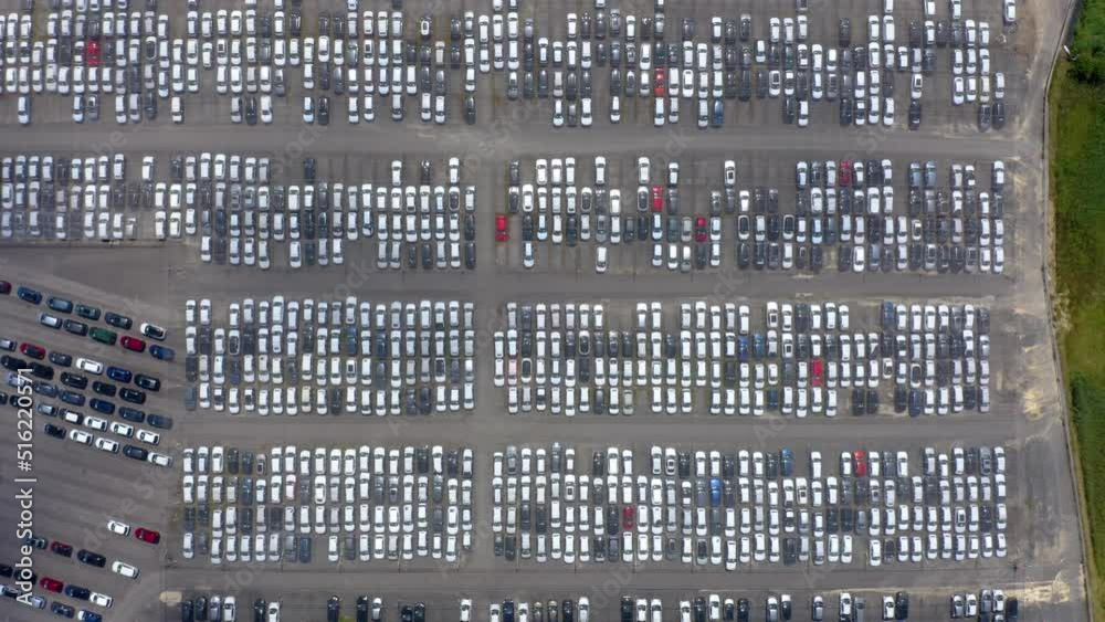 Aerial top view of many cars parked. Aerial shot above a parking area full of cars. multicolored cars on warehouse parking lot. Dealership car lot. Aerial top view of many cars parked. Aerial shot above a parking area full of cars. multicolored cars on warehouse parking lot. Dealership car lot.