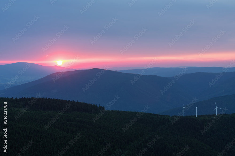 Wind turbines in Bear mountain , view from upper water reservoir of the pumped storage hydro power plant Dlouhe Strane in Jeseniky Mountains, Czech Republic. Summer sunset.