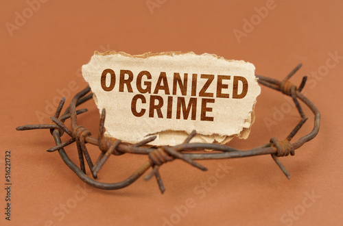 On a brown surface, barbed wire and a cardboard sign with the inscription - Organized Crime photo