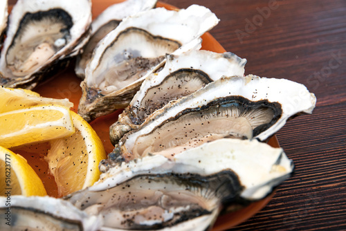 Canvastavla Close up of freshly shucked opened oysters with black pepper and lemon on plate