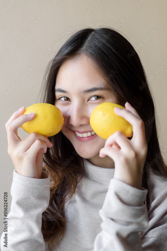 attractive cheerful asian woman holding yellow lemon, beauty and healthy skin care and cosmetic ideas concept attractive cheerful asian woman holding yellow lemon, beauty and healthy skin care and cosmetic ideas concept