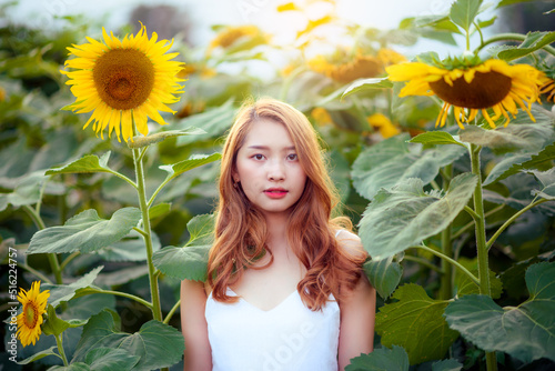 Beautiful young woman in a field of sunflowers at sunset