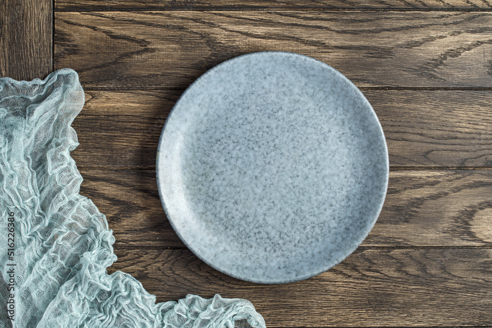 Empty bluish plate and gauze napkin on oak woodentable. Top view, with copy space Empty bluish plate and gauze napkin on oak woodentable. Top view, with copy space