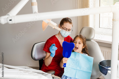Consultation with child dentist at dentistry. Teeth treatment. Child looking in the mirror at the dentist. Happy child patient of dentistry.