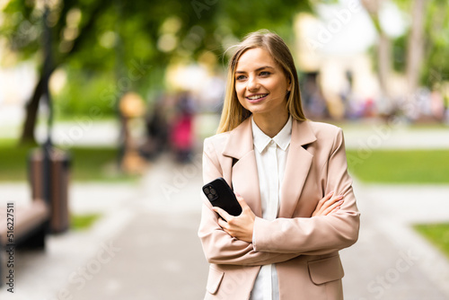 Young woman holding mobile phone outdoors on summer day