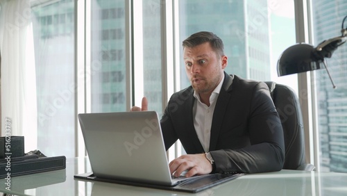 A businessman is concerned about the crisis. Focused serious businessman in suit thinking reading online news or solving business problem working on laptop looking at screen.