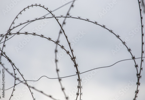 Barbed wire on the background of the sky close-up. Protected area, entrance is prohibited. Danger zone.